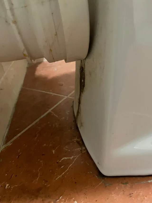 Raccord d'évacuation encrassé au pied d'un WC